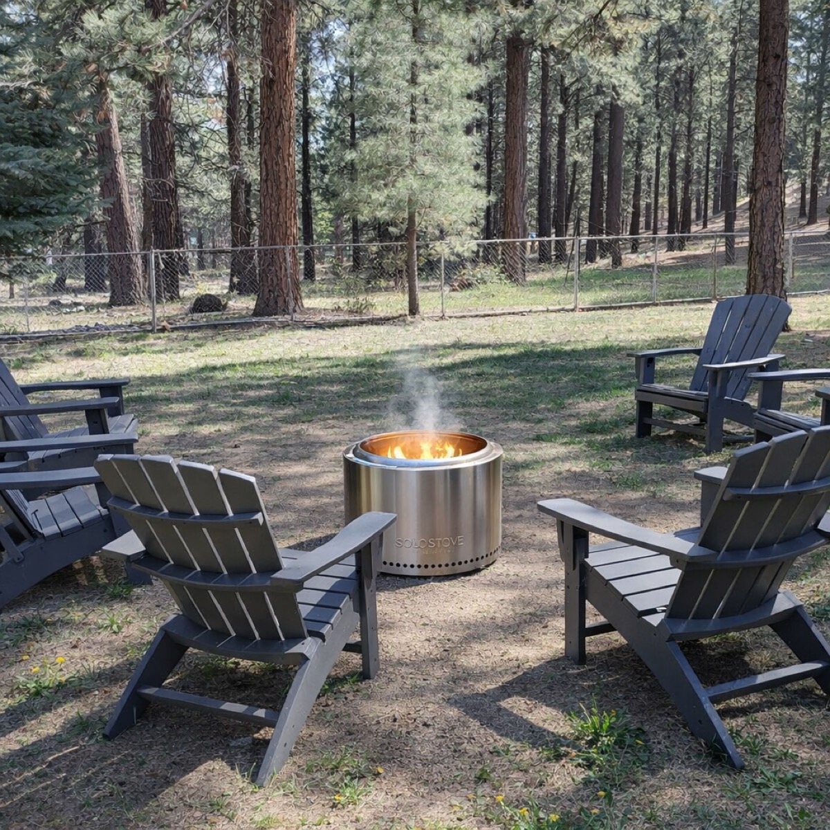 Backyard fire pit area with Adirondack chairs and Solo Stove